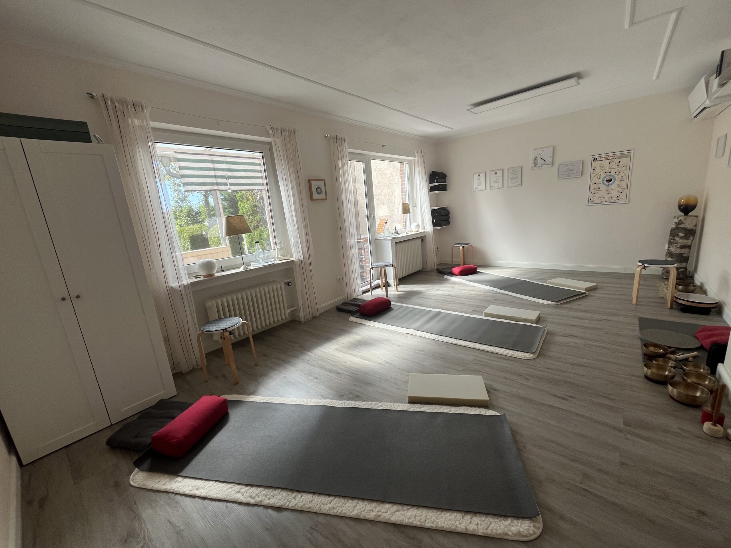 Heller, gemütlicher Yogaraum von YogaJuma mit Yogamatten, Kissen und verschiedenen Yoga-Hilfsmitteln